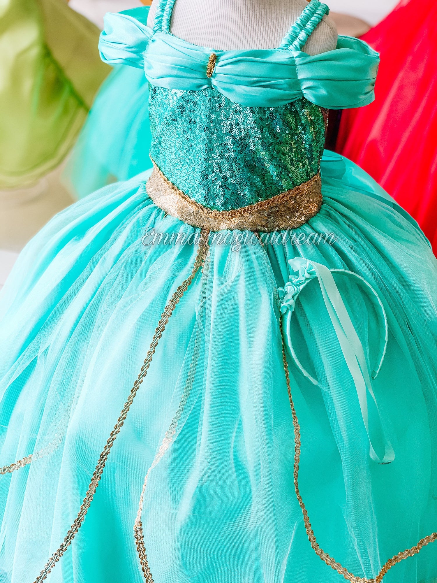 Emma's Magical Dream, Teal dress with tulle, gold accents, and sequin detailed body. Pictured with a headband, off the shoulder sleeves, and spaghetti straps to hold the dress up.  