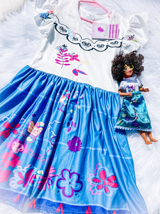 Emma's Magical Dream, blue skirt with printed pink and purple flowers, white top with ruffle sleeves, Maribel doll sitting next to the dress